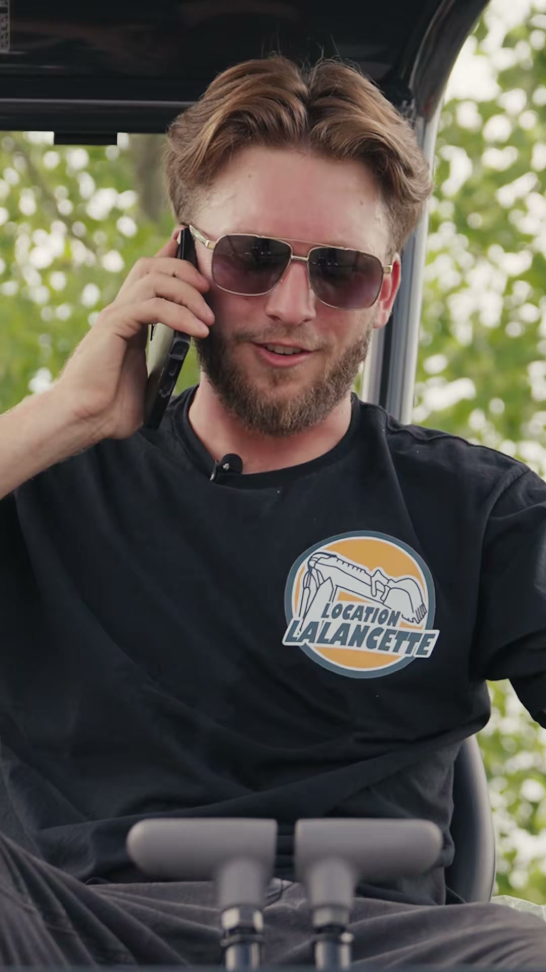 Un membre de l'équipe Location Lalancette au téléphone, assis dans une excavatrice